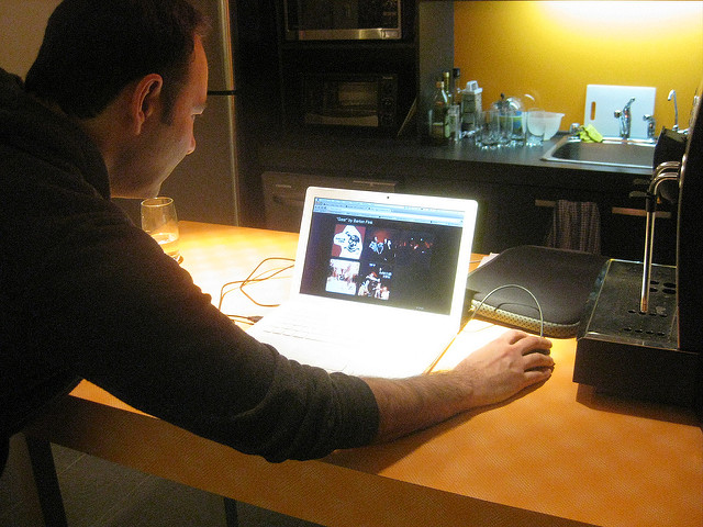 Man hunched in front of laptop looking at screen